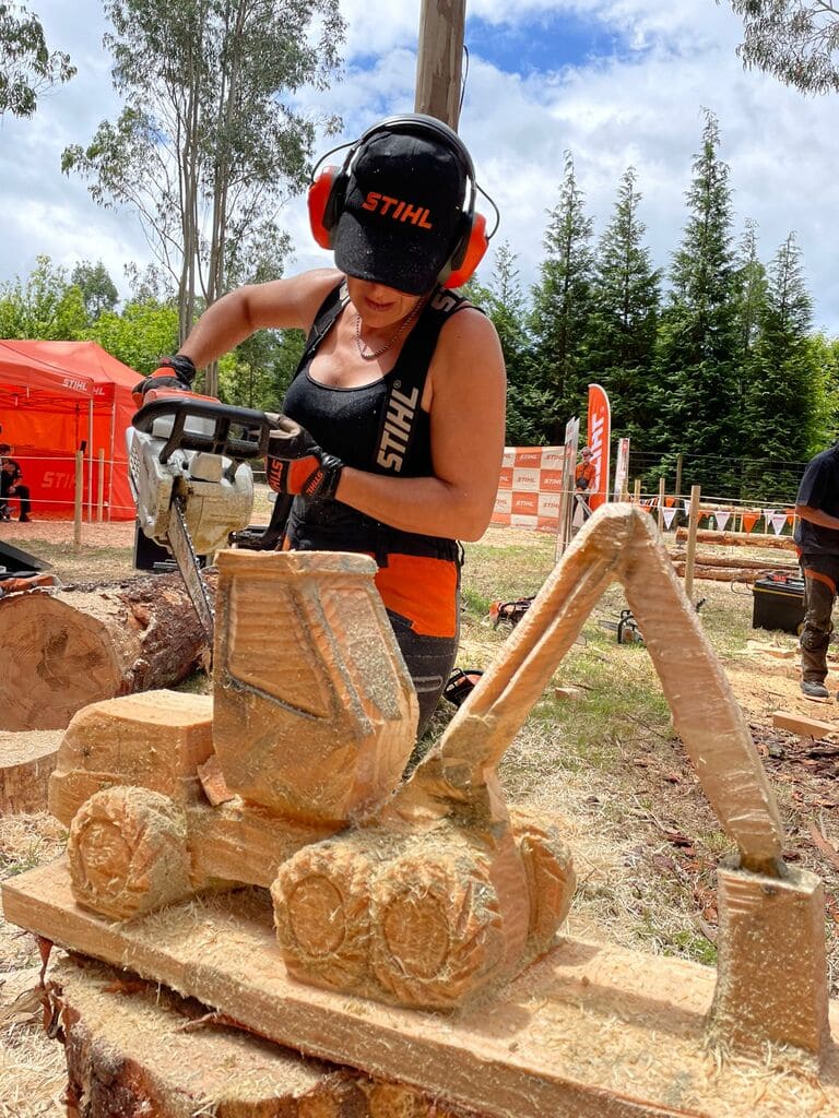 Lupe Arévalo, escultora talentosa, tallando un tractor de madera con el uniforme de Stihl