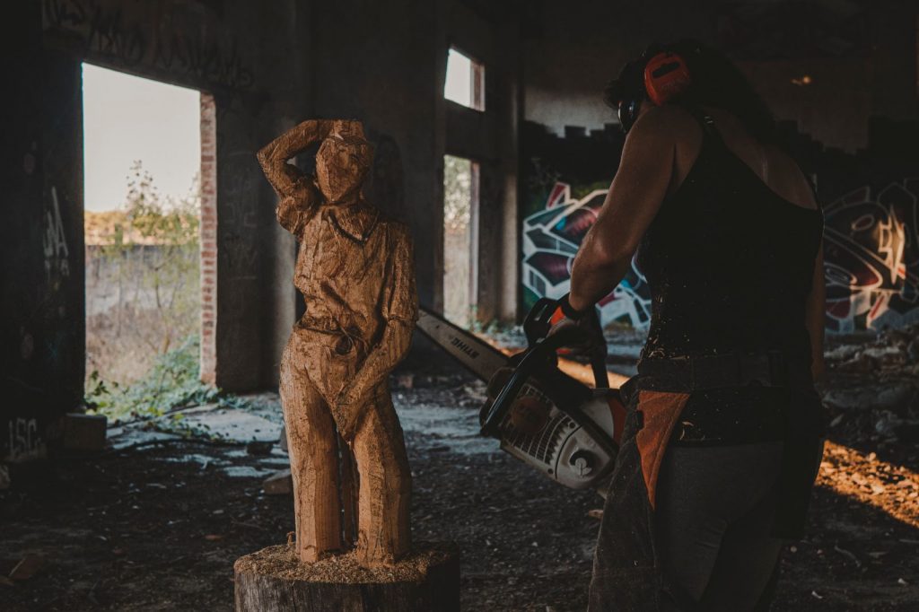 En esta imagen, se puede apreciar a Lupe Arévalo en pleno proceso de tallado de la figura de una mujer en madera.